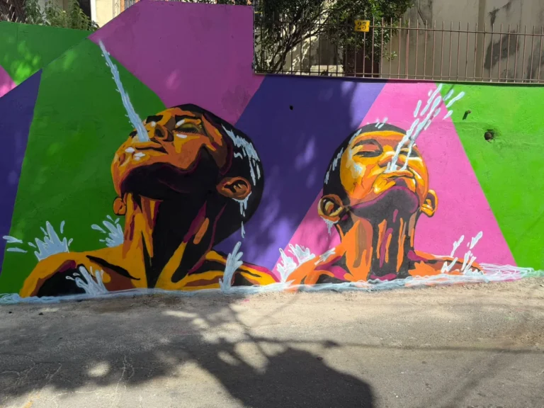 Mural de grafite com crianças cuspindo jatos de água, retratando o costume de banho de mar na “maré” da comunidade de Caratoíra, em Vitória-ES, criado no projeto Vizinho da Arte com apoio da Politintas.