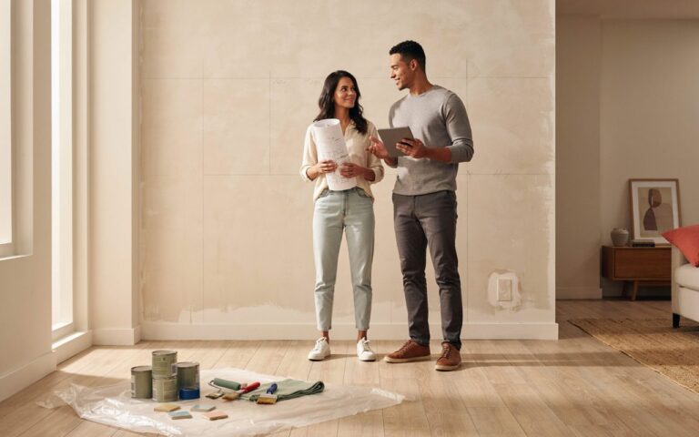 Pessoas sorrindo e planejando a reforma da casa com prancheta em mãos, com foco em organização e economia.